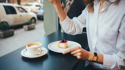 Young woman eating cheesecake drinking coffee