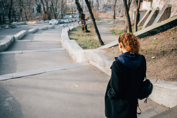 Back view of young woman dressed in black coat and backpack