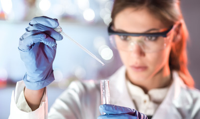 Life scientists researching in laboratory. Focused female life science professional pipetting...