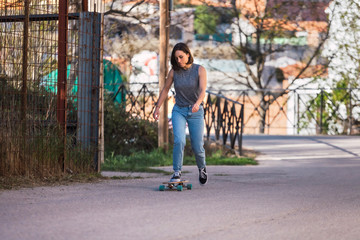 Obraz premium Young skater woman riding on her longboard in the village