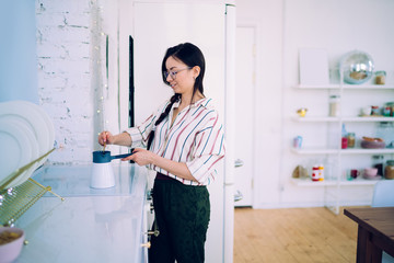 Charming lady making coffee at home