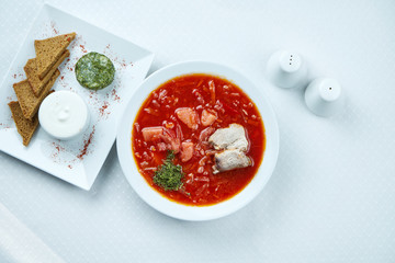 Delicious Ukrainian borsch with pork, lard, sour cream and rye bread on a white background. Top view. Copy space. Restaurant serving