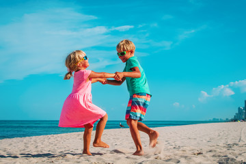 happy boy and girl dance at beach, kids enjoy vacation