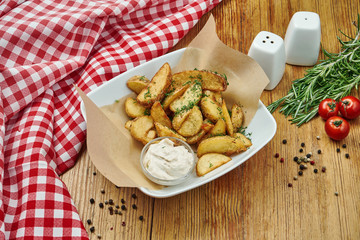 French fries in craft paper on a gray plate on a wooden background. American traditional fast food. Street food