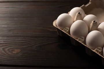 white chicken eggs in egg tray on dark wooden background