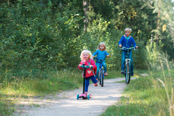happy active kids on bike and scooter ride in nature