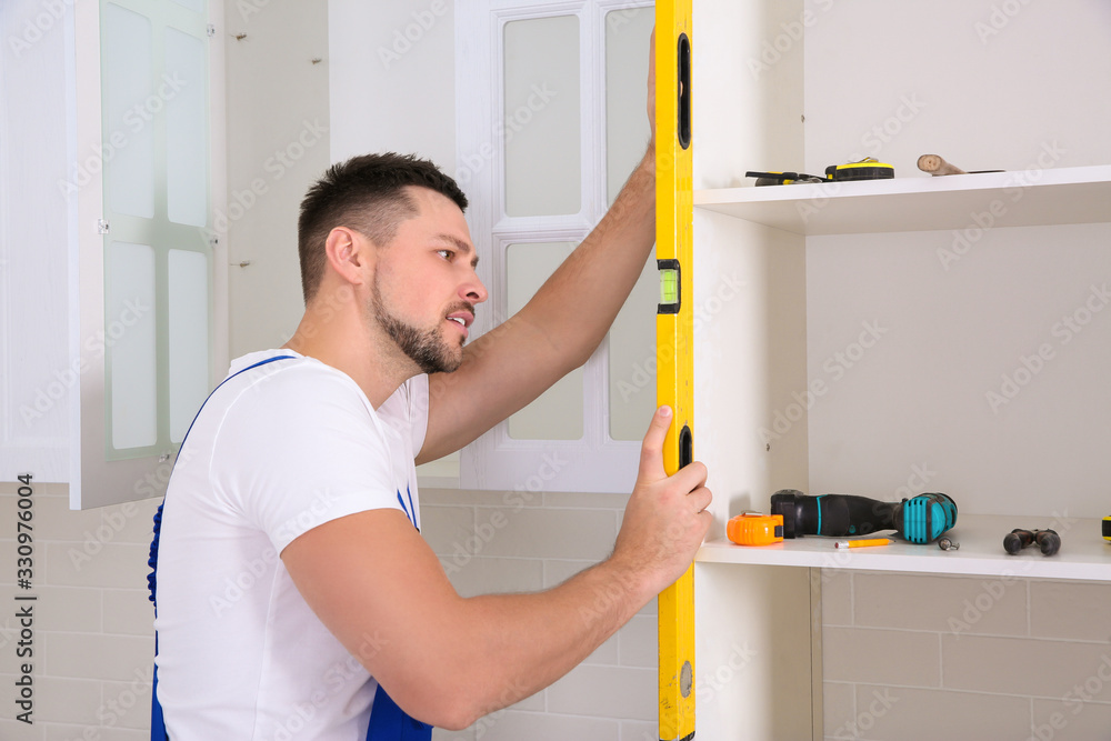 Sticker worker measuring newly installed kitchen furniture indoors