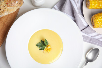 Delicious corn cream soup served on white table, flat lay