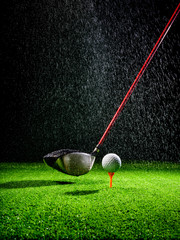 Beam of light in the rain illuminating a golf driver and golf ball on the turf