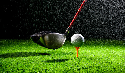 Horizontal close up shot of a golf ball and golf club driver wet from the rain