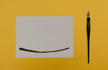 Calligraphy pen on blank colored paper with ink spots