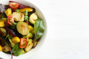 Delicious salad with roasted Brussels sprouts on white wooden table, top view. Space for text