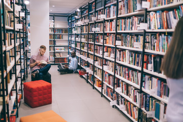 People chilling among bookshelves in library