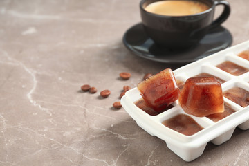 Ice cube tray with frozen coffee on grey table, closeup. Space for text