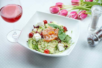 Salad with salmon, mix of leaves, cherry tomatoes and avocado in white bowl. Useful and healthy food. Close up view