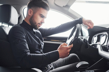 Man in elegant clothes sitting in brand new expencive automobile