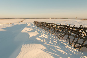 agricultural wooden fence to keep snow in the fields in winter