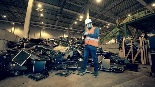 Male worker is examining a pile of broken computers