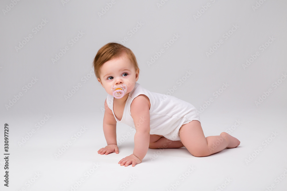 Wall mural baby with a pacifier in his mouth on a white background, space for text