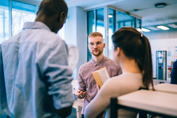 Redhead male student helping friends with preparation for exam