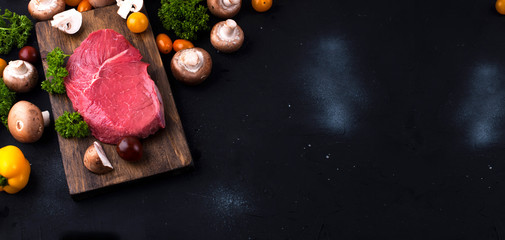 Beef. Red meat, different vegetables for cooking on a black stone table. Banner long format. Copy space