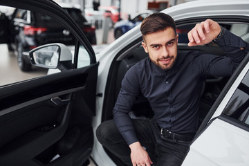 Young man in formal clothes is near brand new expensive car