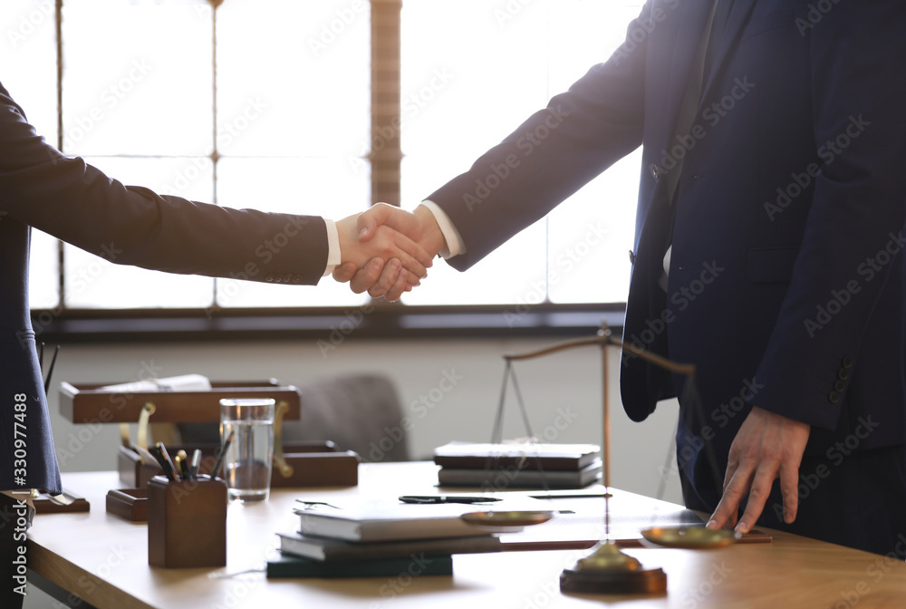 Wall mural Male lawyer shaking hands with client in office, closeup