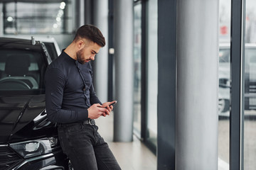 Young man in formal clothes is near brand new expensive car