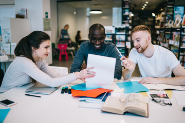 Joyful friend looking at paper while studying together