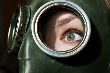 Face of young girl wearing a gas mask, cropped shot.  Frightened look of a girl in a gas mask. Panic, war, people, epidemic concept.