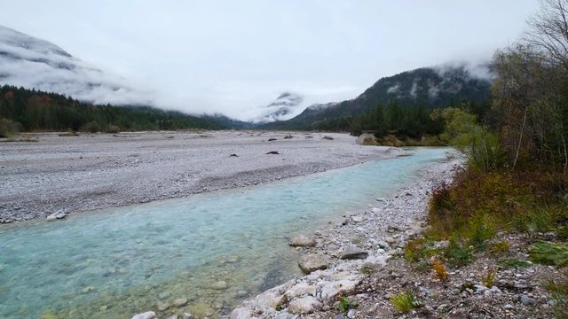 Autumn overcast day on Karwendel Bavarian Prealps and Isar river flow, Germany. Picturesque traveling, seasonal and nature beauty concept scene.