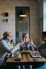 women friends making toast with wine in restaurant