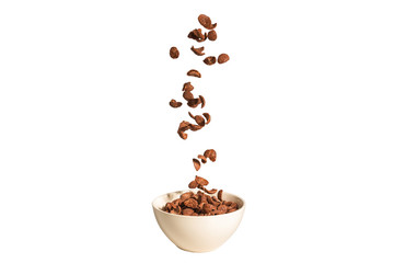 Chocolate corn flakes falling to the white bowl isolated on white. Motion.