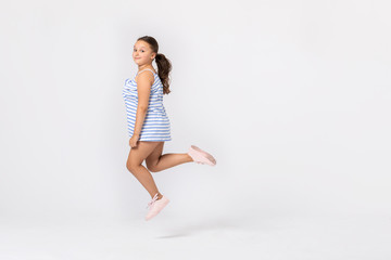 Cute teenage girl jumping in the empty room, copy space on the white wall