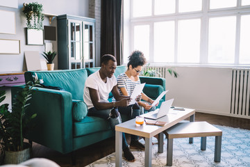 Busy black couple doing paperwork at home
