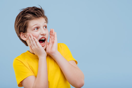 excited young boy look aneway and screaming in yellow t-shirt isolated on yellow background, copy space