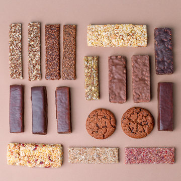 Row Of Mixed Gluten Free Granola Cereal Energy Bar With Dried Fruit & Various Nuts And Protein Snack On Brown Background. Healthy Vegan Super Food, Fitness Dieting Snack For Sporty Lifestyle