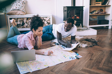 Modern diverse couple planning trip at home