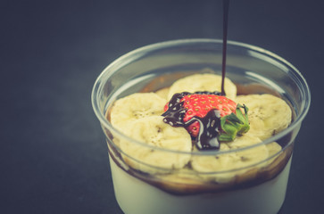Pour sauce chocolate fresh milk pudding with sliced banana and strawberry