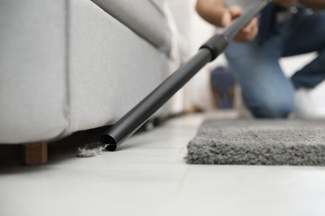 Naklejka premium Young man using vacuum cleaner at home, closeup
