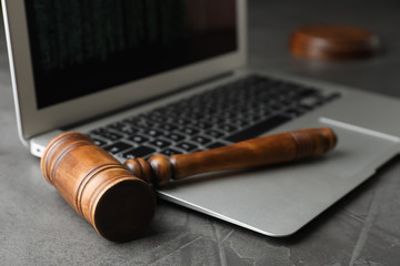 Laptop and wooden gavel on grey table, closeup. Cyber crime