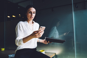 Surprised businesswoman looking at smartphone screen