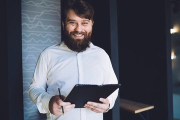 Bearded employee with clipboard looking at camera