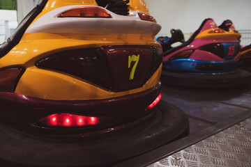 Empty bumper cars with glowing lights at the amusement park. Fairground with attractions. Colorful dodgems.