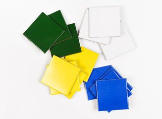 Pile of samples of tiles in different colours: green, yellow, blue and white. Isolated on white background.