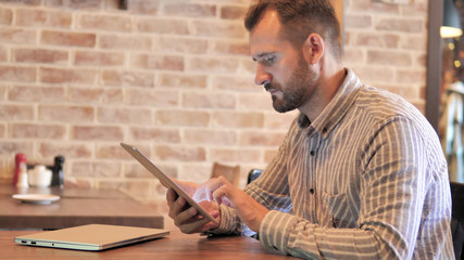 Beard Casual Man Using Tablet while Sitting Outdoor