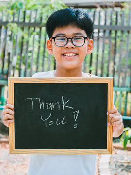 Asian boy holding a blackboard with the words Thank You with smile.