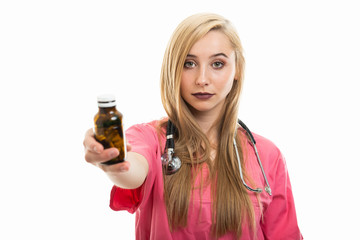 Portrait of female doctor wearing scrubs handing bottle of pills