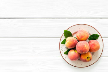 Summer fruits. Ripe red peaches on plate on white wooden table top-down copy space