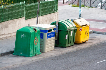 Four types of waste collection and recycling containers on the sidewalk of a street in San Sebastián de los Reyes. Glass, paper, organic, packaging.